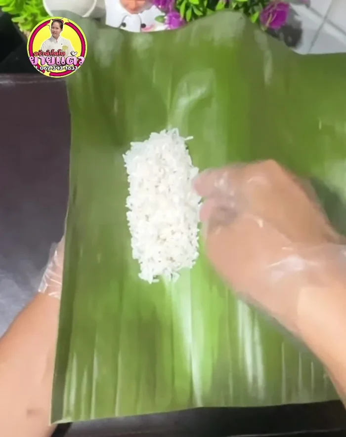 Assemble the Khao Tom Mat: Place a banana piece at the bottom of a banana leaf, followed by a portion of soaked glutinous rice and black beans. Roll and wrap the banana leaf tightly but not too much, to prevent it from breaking during cooking.