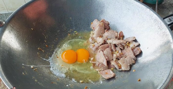 Crack two eggs into the pan and stir-fry until cooked.