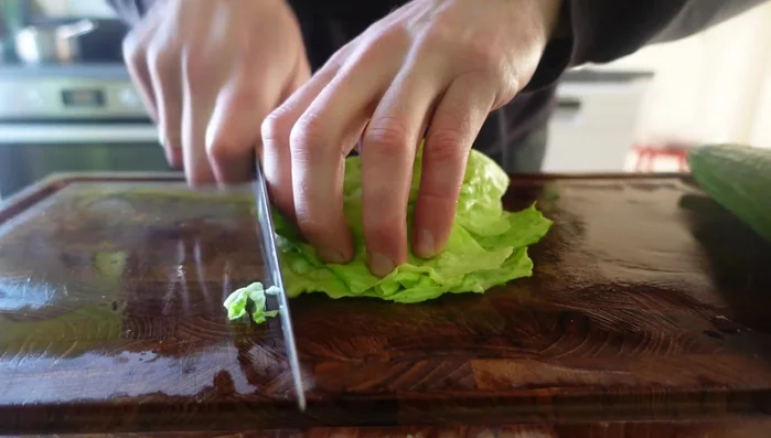 Prepare the Crying Tiger Steak garnish: Shred iceberg lettuce, peel and slice cucumber on a bias, and slice tomatoes. (584.04)