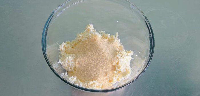 In a mixing bowl, combine the grated cassava, sugar, and water. Mix well until combined.