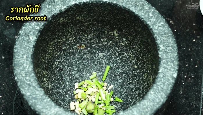 Pound together peppercorns, coriander roots, and garlic in a mortar.