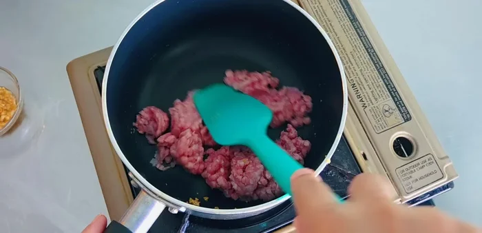 Add minced pork to the pot and stir-fry until cooked.