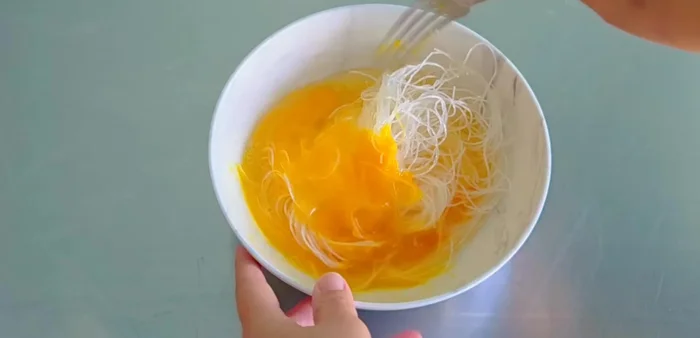 Mix soaked glass noodles with eggs.