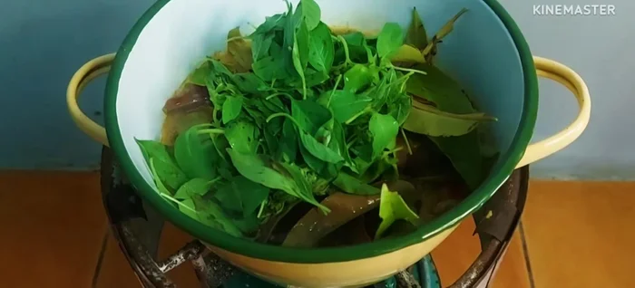 Add the water spinach and betel leaves to the curry. Allow them to wilt in the simmering liquid.