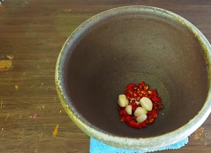 Add red chili peppers, garlic to a mortar and pestle. Pound until finely ground. Adjust the amount of chili to your desired level of spiciness.