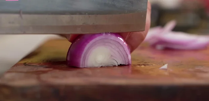 Cut the onion into halves and then into thin long slices.