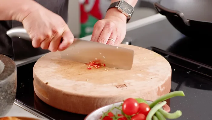 In a pestle and mortar, start building the dressing: Pound the garlic, chili, and cherry tomatoes to release their juices and add flavor.