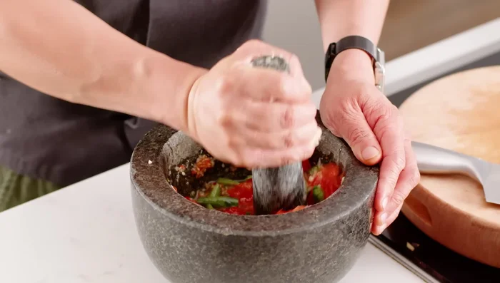 Add the fish sauce and sugar to the pestle and mortar, and mix well to create the dressing.