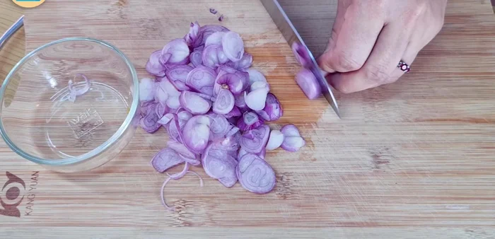 Prepare the vegetables: thinly slice shallots, chop spring onion greens, and separate mint, basil, and cilantro leaves.