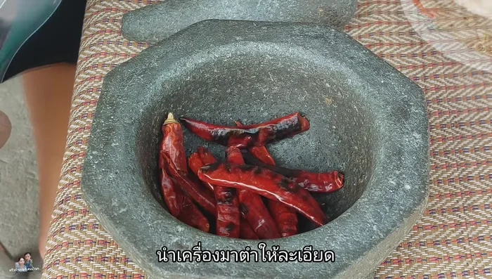 Pound the roasted chilies, shallots, garlic, and lemongrass together.