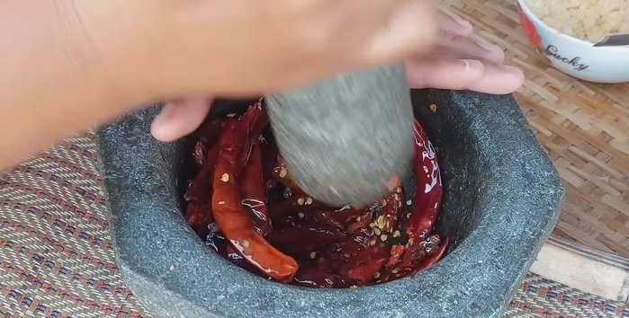 Pound the fried chilies, shallots, and garlic until finely ground. Add shrimp paste and pound again until smooth.