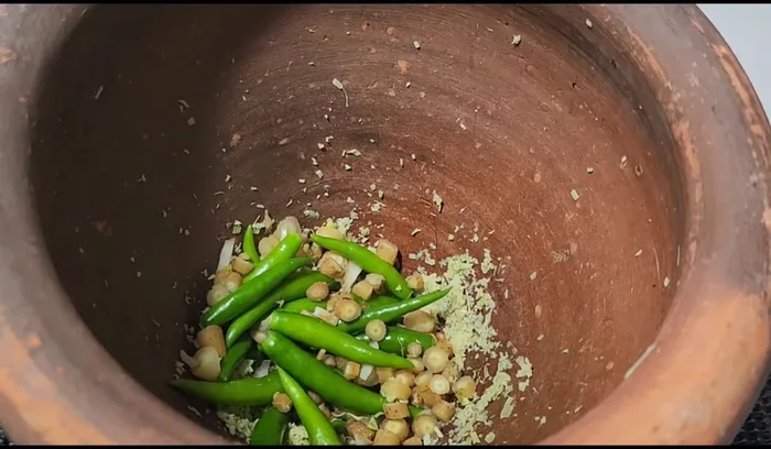 Add green chilies and continue pounding.