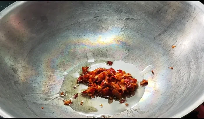 Stir-fry the aromatics: Heat oil in a pan, add the pounded chilies and garlic, and stir-fry until fragrant.