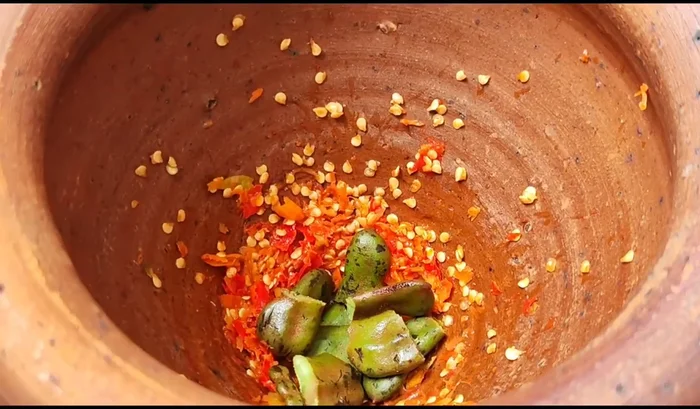 Add the young tamarind to the pounded chilies and continue to pound until finely ground.