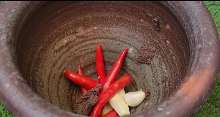 Pound garlic, chili peppers, and shrimp paste together.
