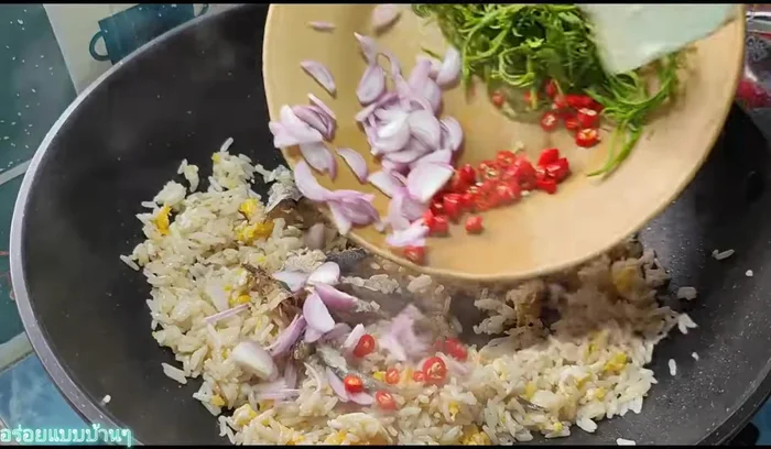 Add the mackerel, shallots, sliced chili, and cha-om. Stir-fry until the cha-om is cooked and everything is well mixed.