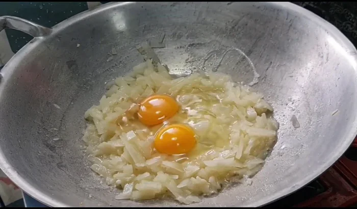 Crack the eggs into the pan and scramble them.