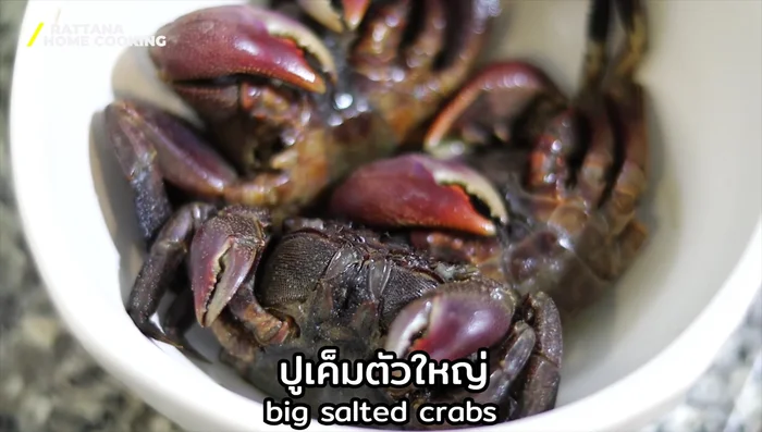 Add the tomatoes, long beans, and salted crab, continuing to pound gently.