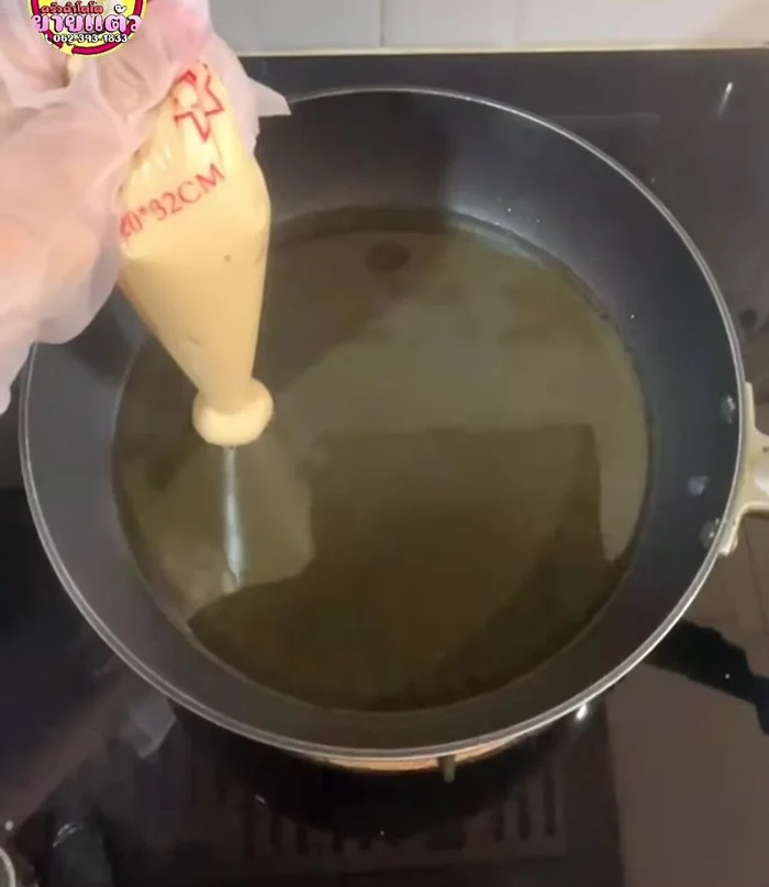 Squeeze the dough into the hot oil, pressing it to the bottom of the pan to prevent floating. Use scissors to cut the dough if needed.