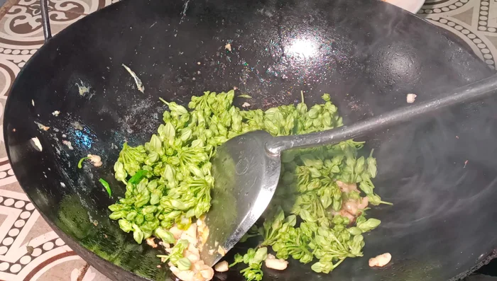 Add the Dok Khaojor and other vegetables to the wok. Stir-fry until slightly softened.