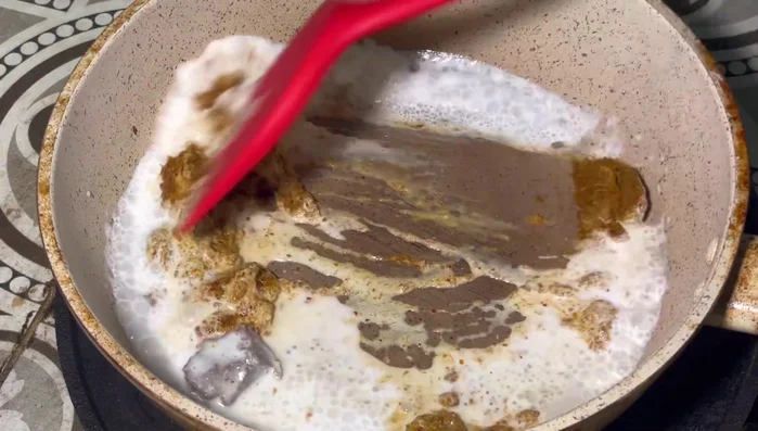 Cut the curry paste and shrimp paste. Let it dissolve into the coconut cream. Use a spatula to slowly press and mash it until it dissolves. Then slowly add another portion of the coconut cream and stir to mix.
