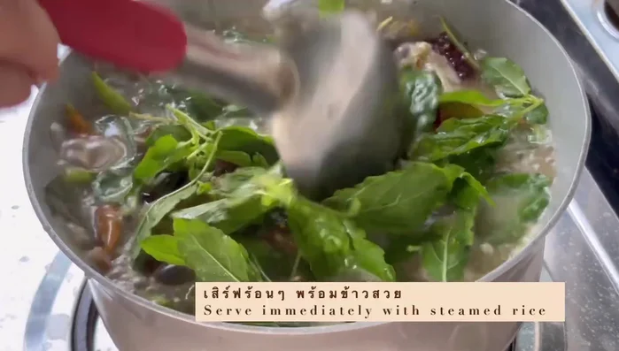 Garnish with holy basil leaves and spring onions. (Implied)