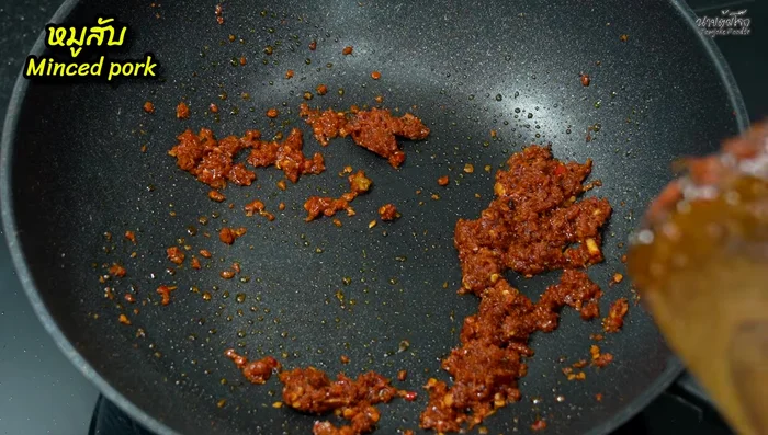 Add minced pork to the pan and stir-fry with the curry paste, increasing the heat to medium-high. Stir-fry until the pork is cooked through.