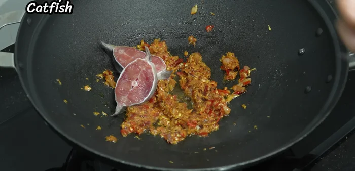 Add the prepared catfish and stir-fry until partially cooked, ensuring it doesn't stick to the pan.