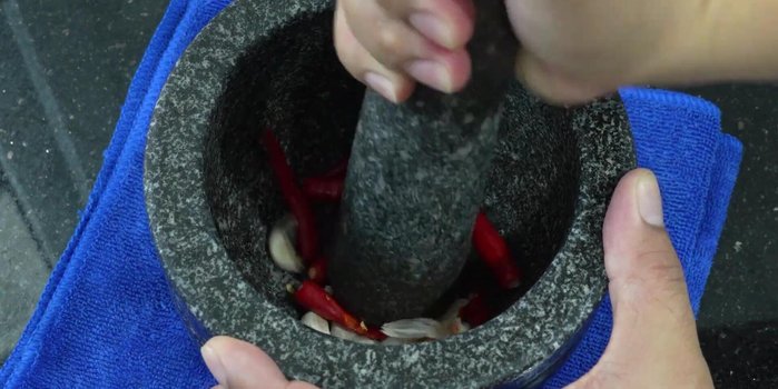 Pound garlic and chili peppers together in a mortar and pestle to your desired level of crushed-ness. (If you like it spicy, add more chili).