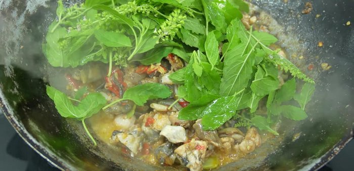 Add holy basil leaves and flowers. Stir-fry over high heat until everything is cooked and the basil is fragrant.