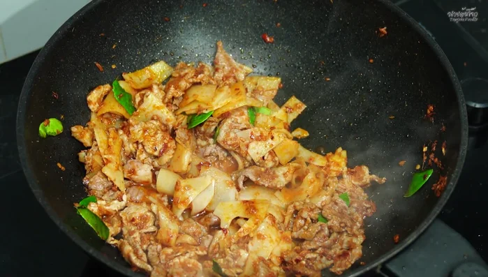 Season with fish sauce, seasoning powder, palm sugar, and chili peppers. Stir-fry until the sugar melts and the chili peppers soften.