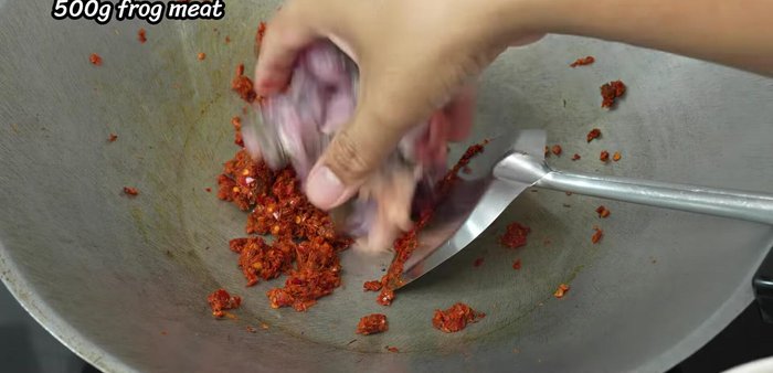 Add the frog meat and stir-fry until it starts to cook. Drain excess water from the frog meat before adding it to the pan.
