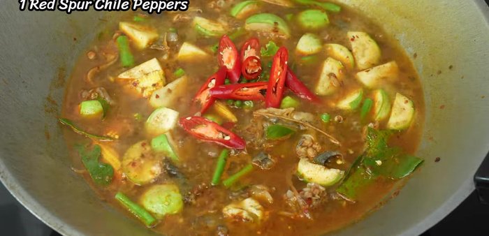 Add remaining kaffir lime leaves, sliced chili peppers, and green peas.