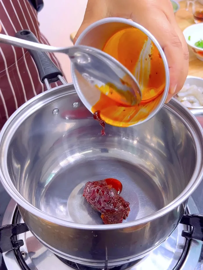 In a pan, mix 1.5 tablespoons of tom yum chili paste with 4 tablespoons of coconut milk over low heat until boiling.