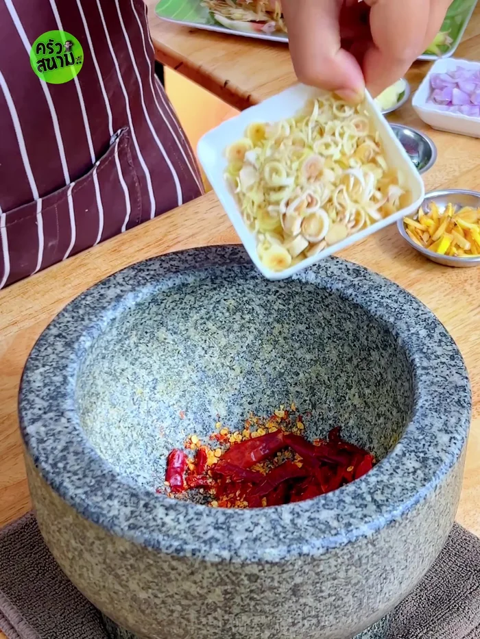 Add lemongrass, galangal, makrut lime leaves, and salt to the chilies; pound roughly.