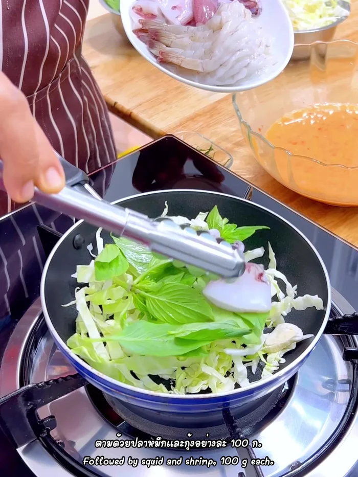 Add 100g each of squid and shrimp to the pan.