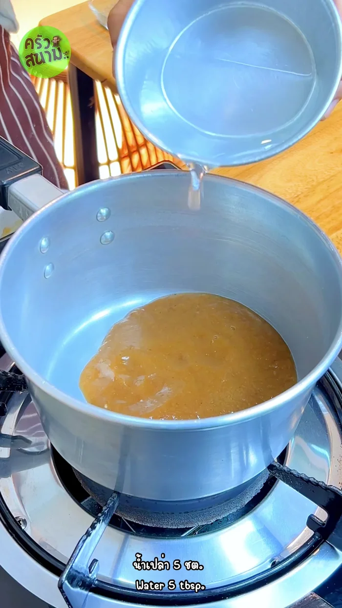Make the nam jim jaew: Simmer tamarind juice, water, fish sauce, and sugar until thickened. [145.28]