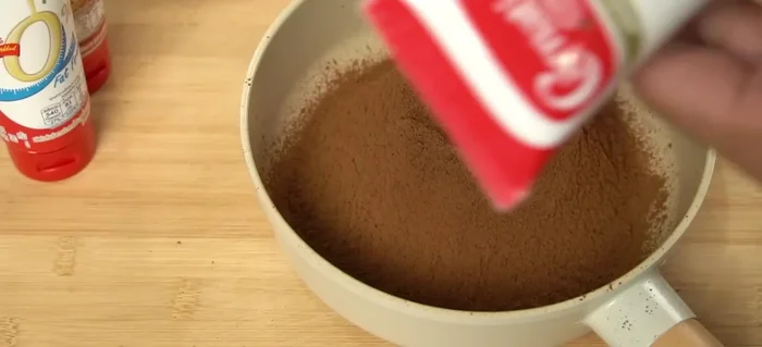 Add condensed milk to the sifted cocoa powder. The amount depends on your desired sweetness and thickness; start with a moderate amount and adjust as needed.