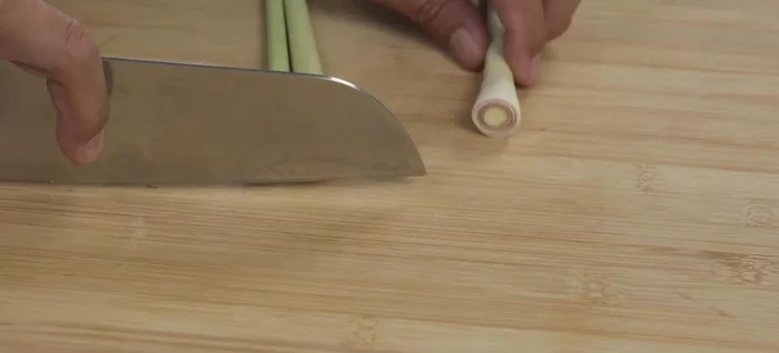 Prepare Tom Yum ingredients: Wash and clean lemongrass, removing old parts and leaves. Finely slice lemongrass, red onion, and kaffir lime leaves. Chop chilies (adjust to spice preference).