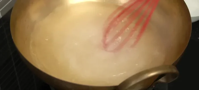 In a saucepan, bring water to a boil. Add sugar and stir until dissolved.