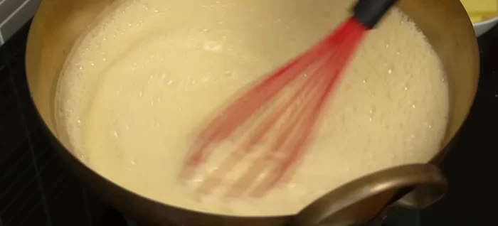 Slowly pour the milk/flour mixture into the boiling sugar syrup, stirring constantly to prevent lumps. Continue stirring until the mixture thickens and boils for 1-2 minutes.
