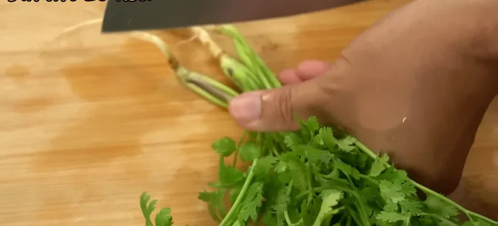 Prepare the coriander: Wash the roots well, crush slightly, and set aside the leaves for garnish.