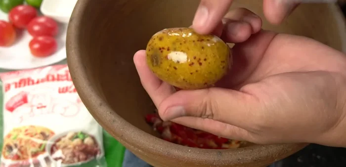 Add olives, green beans, and other papaya salad ingredients to the mortar and pestle.
