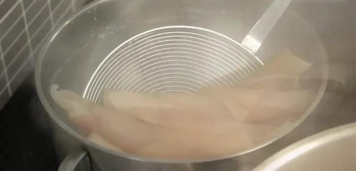 Drain the water and set the boiled pig skin aside.