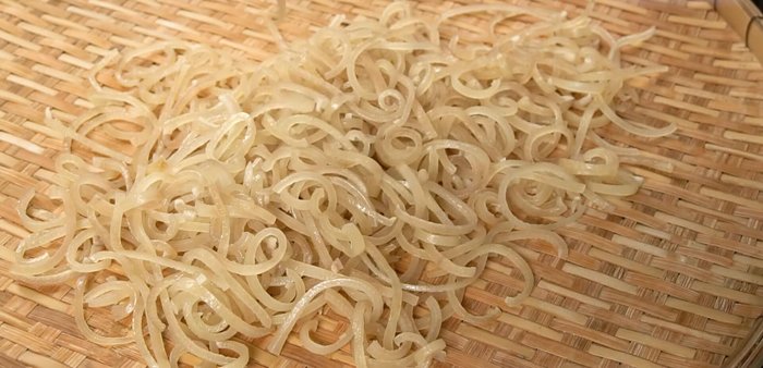 Spread the seasoned pig skin evenly on a winnowing basket or tray and dry it in the sun until completely dry. Alternatively, use low heat to dry it indoors.