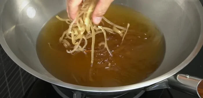 Carefully add the dried pig skin to the hot oil. Fry until puffed, crispy, and lightly browned, stirring occasionally to ensure even cooking. Be mindful of oil temperature to avoid burning.