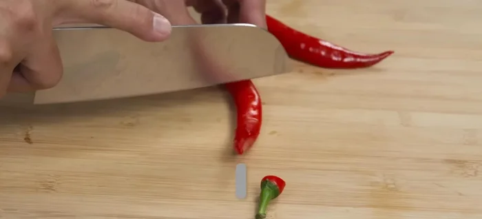 Thinly slice red chili peppers, removing seeds and soaking them in water to soften.