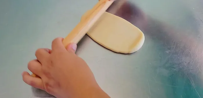 Flatten a piece of outer dough, place a piece of inner dough on top, and flatten again. Add a filling ball and wrap tightly, pinching the edges to seal.