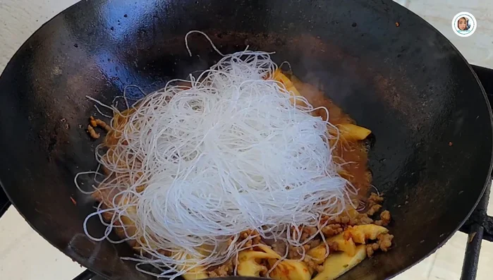 Add soaked glass noodles and stir-fry until soft. Add more water if needed.