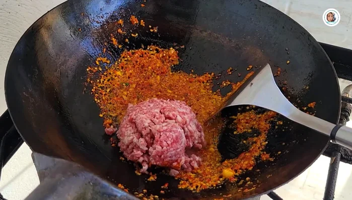 Add minced pork and stir-fry until it starts to cook. Add water.